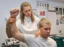 Clinician evaluating an adult patient’s shoulder during a clinic visit